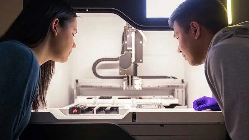 Female and male student looking into rapid prototyping machine.