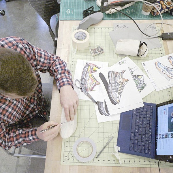Overhead shot of man creating product designs for athletics shoes.